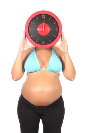 beautiful pregnant woman holding clock in handsの写真素材
