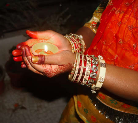 indian woman wears traditional bangles in hand and holding diya dip deepak oil lamp on hand. Its indian festival to celebrate their culture. On this day woman  draw mehndi design on hand.のeditorial素材