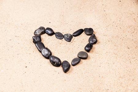 heart drawn with pebbles on the beach sandの写真素材