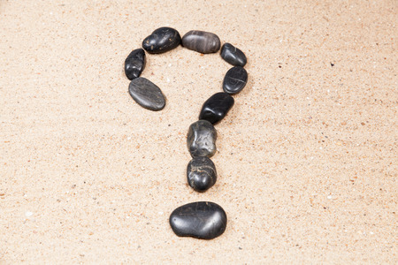 question mark drawn with pebbles on the sand of a beachの写真素材