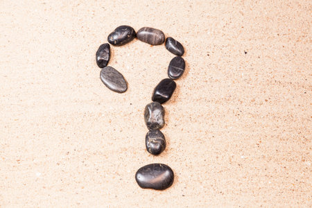 question mark drawn with pebbles on the sand of a beachの写真素材