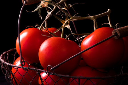 big red tomatoes on black background in light dark ready to cookの写真素材