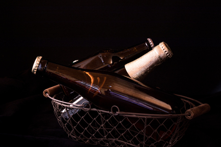 beer bottles on a black background chiaroscuro in an old metal mesh basketの写真素材
