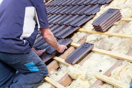 a roofer laying tile on the roofの写真素材