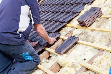 a roofer laying tile on the roof