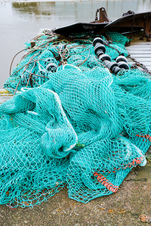 blue fishing net on a pontoon with its ropes and floats covered with morning frost