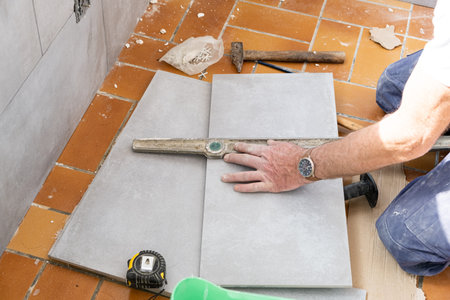 the tiler measures the tile before cutting it