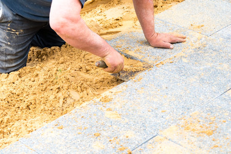 the mason lays gravel slabs on sand to make an alleyの写真素材