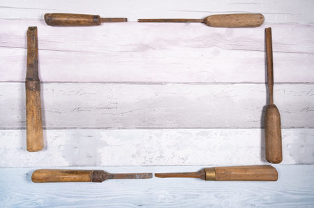Old wood chisels forming a frame on a background of old boards. Top view with space for text