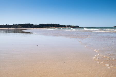 Large sandy beach in the town of "Sables d'or les pins" in Brittany at low tide in summer.の写真素材