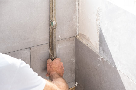the tiler lays a ceramic tile on the wall