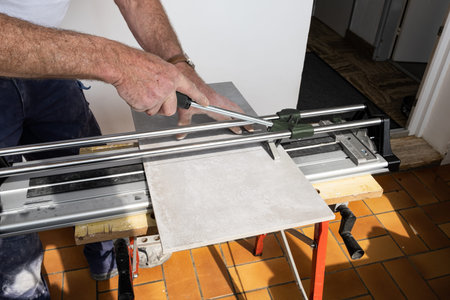 the mason cuts a ceramic tile with a tile cutter