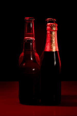 silhouettes of four beer bottles on a black background and lit with red light.の写真素材