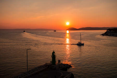 Sunset over the Adriatic Sea and its boats playing in the reflections at the entrance to the port of Split in Croatia.の写真素材