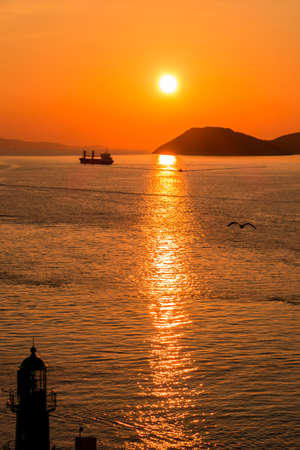 Sunset over the Adriatic Sea and its boats playing in the reflections at the entrance to the port of Split in Croatia.の写真素材