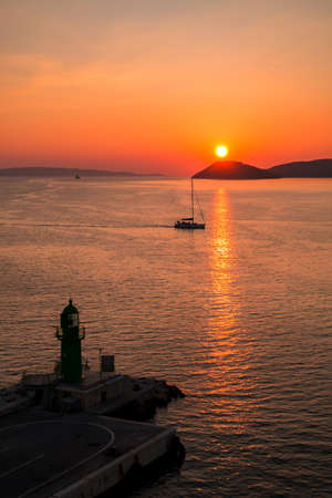 Sunset over the Adriatic Sea and its boats playing in the reflections at the entrance to the port of Split in Croatia.の写真素材