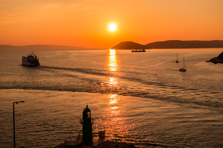 Sunset over the Adriatic Sea and its boats playing in the reflections at the entrance to the port of Split in Croatia.の写真素材