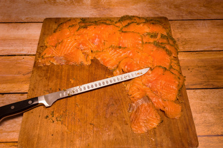 Artisanal smoked salmon covered with dill and spices on a wooden board.
