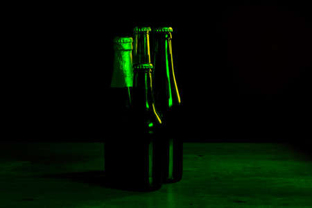 silhouettes of four beer bottles on a black background with green lights that illuminate them on one side.の写真素材