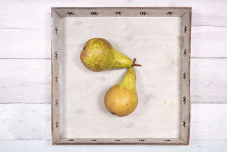 two conference pears placed in an old wooden tray on an old wooden floor.の写真素材
