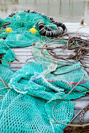 blue fishing net on a pontoon with its ropes and floats covered with morning frostの写真素材