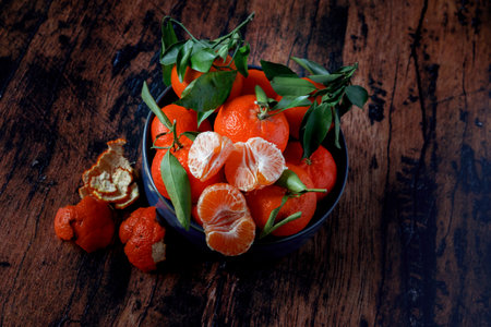 Clementines with leaves in a blue ceramic dish on an old wooden tableの写真素材