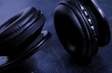 Close up picture of black headphones on black board and light from the right side