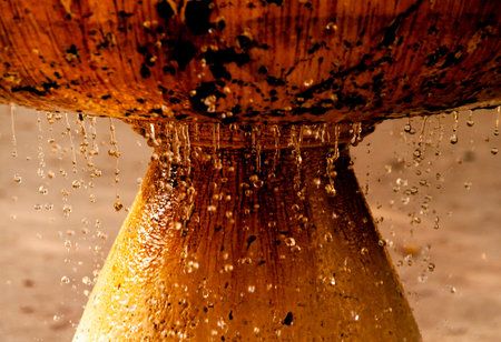 Straight on picture of drops falling from orange stone fountain
