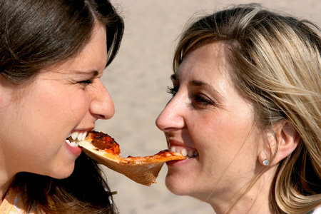 Two girls fight over a slice of pizzeの写真素材
