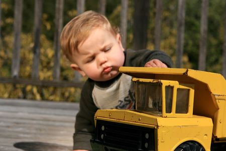 A cute little boy plays with a yellow truckの写真素材