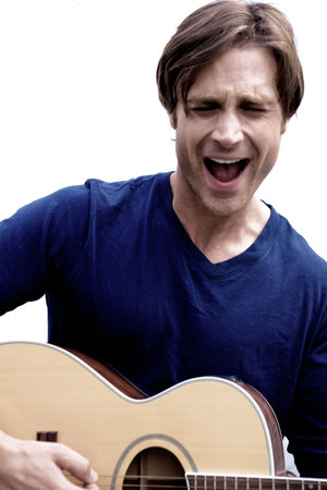 An attractive guitar player with a blue shirt and white backround