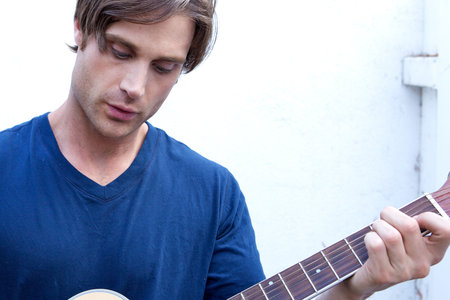 An attractive guitar player with a blue shirt and white backround