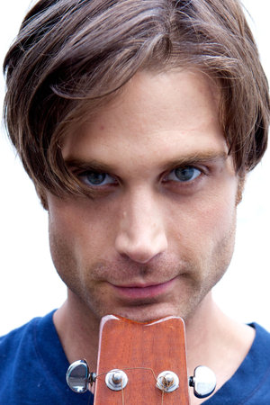 An attractive guitar player with a blue shirt and white backround