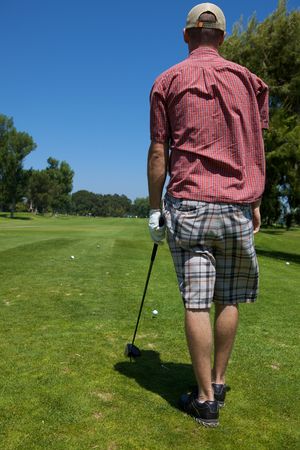A golf player preparing to swing lining up shotの写真素材
