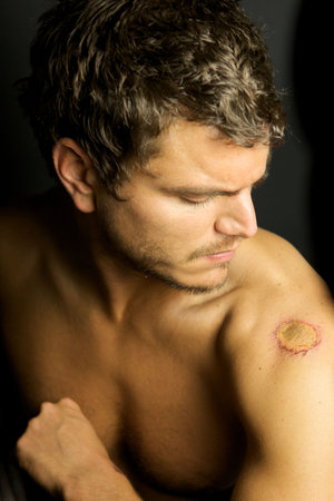 An Edgy Youth with no shirt a cuts with a serious lookの写真素材