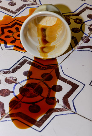 a white porcelain coffee cup, simulating a white plastic cup from coffee vending machines fallen on the floor of a kitchen of an old house with tiles with old geometric patterns anの写真素材