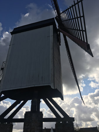 Vintage windmill located on a green mound and blue sky in Bruges, Belgium.の写真素材