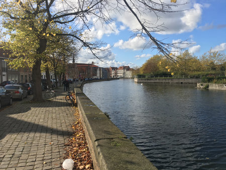 Bruges, Belgium - 8 May 2024: Famous view of Bruges tourist landmark attraction - Rozenhoedkaai canal with Belfry and old houses along canal with tree and tourist boat. Brugge, Belgiumの写真素材