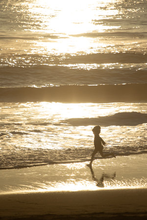 Sunset in the background with people in silhouette, outdoor, kid playingの写真素材