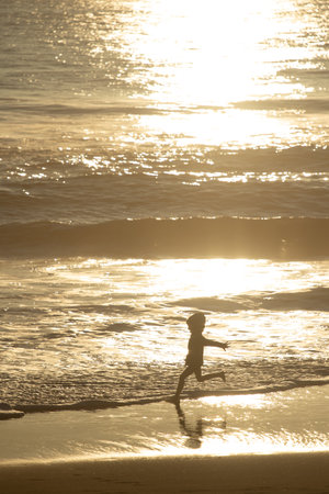 Sunset in the background with people in silhouette, outdoor, kid playingの写真素材