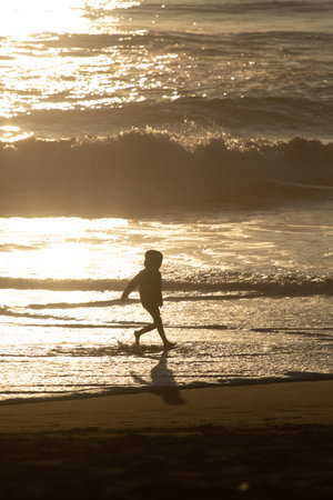 Sunset in the background with people in silhouette, outdoor, kid playingの写真素材