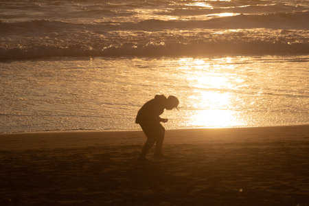 Sunset in the background with people in silhouette, outdoor, kid playingの写真素材