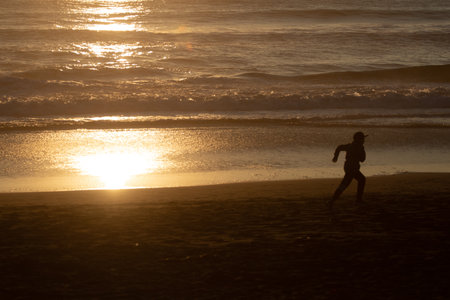 Sunset in the background with people in silhouette, outdoor, kid playingの写真素材