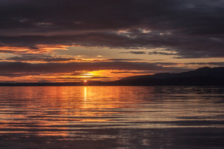 Sunset lighting up the ocean waves along the coast, with vibrant sky colors and relaxing beach atmosphere.の写真素材