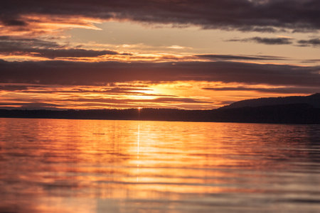 Golden sunset lighting up the ocean waves along the coast, with vibrant sky colors and relaxing beach atmosphere.の写真素材
