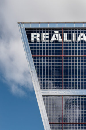 Realia building with glass facade and mesh grille under a cloudy skyの写真素材