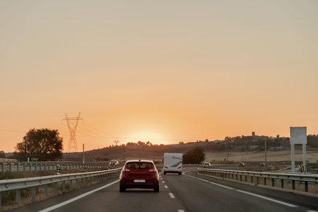 Vehicle on asphalt road, under sunset sky, driving on thoroughfare