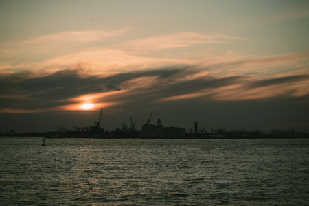 A stunning sunset lights up the water with a city skyline behindの写真素材