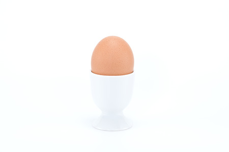 Boiled egg in egg cup on white background.の写真素材