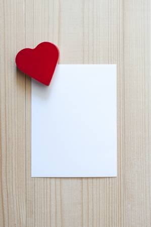 Red heart with white card on wood. Love and Valentines concept. White blank card.の写真素材